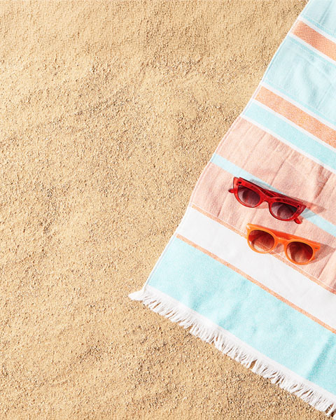 Handtuch und zwei sonnenbrillen im sand