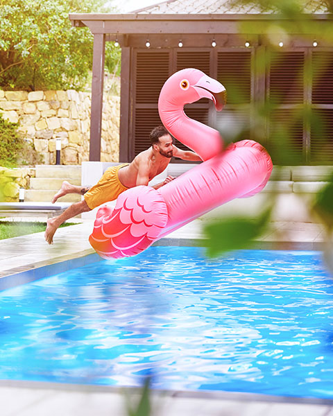 Person auf Flamingo-Schwimmreifen in einem Pool