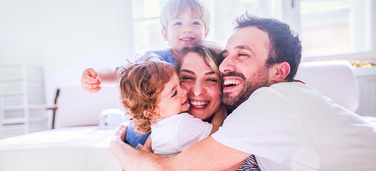 Frau, Mann und zwei Kinder in Umarmung